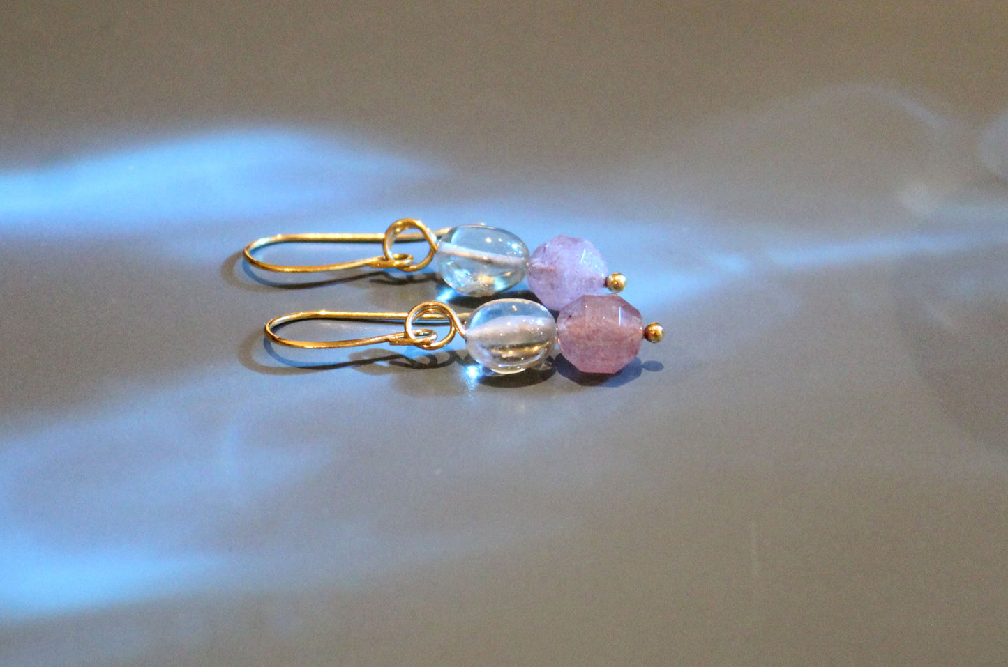 Prasiolite and strawberry quartz gold drop earrings styled in soft light