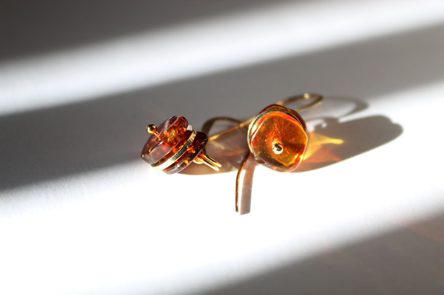 Amber gold drop earrings styled in warm natural light