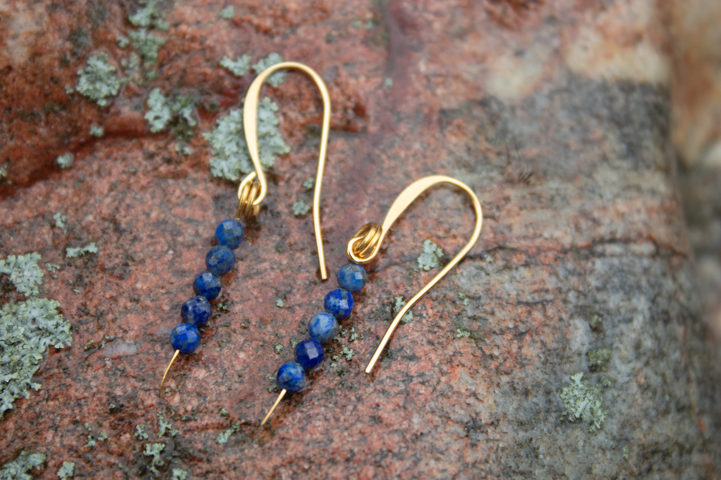 Lapis lazuli gold drop earrings styled on stone