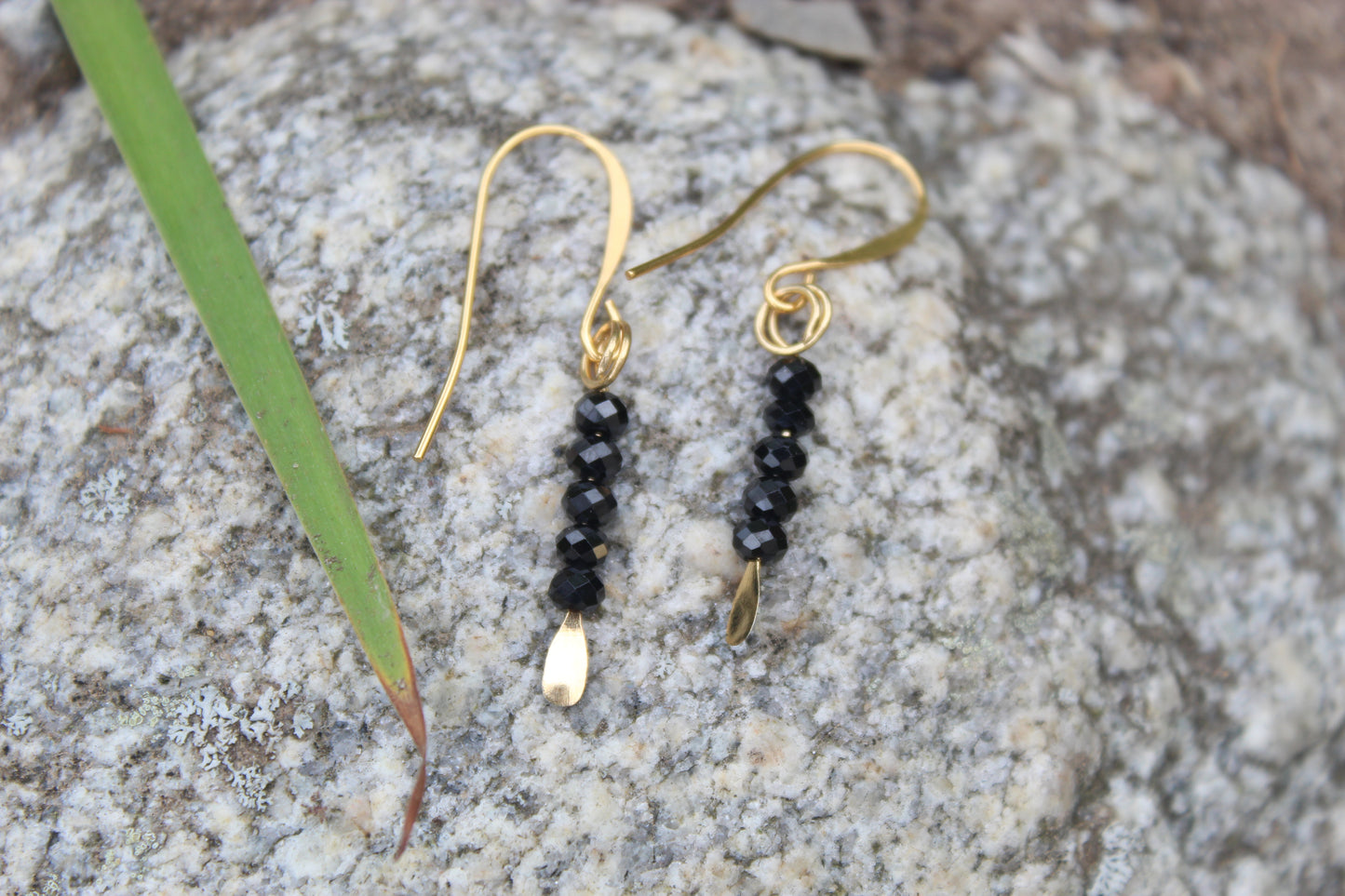 Black spinel gemstone drop earrings styled outdoors