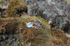 Blue iolite gold drop earrings styled on natural rock