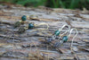 Moss agate gold pine cone drop earrings styled on wood
